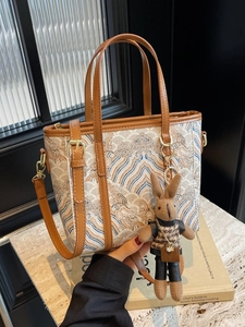 Retro patterned fabric bucket bag with brown leather handles and a plush rabbit charm