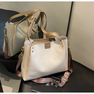 Dettaglio della borsa tote crema con tracolla geometrica e accenti di borchie in metallo