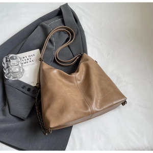 Detail view of large brown tote bag with geometric stitching and metal chain accents