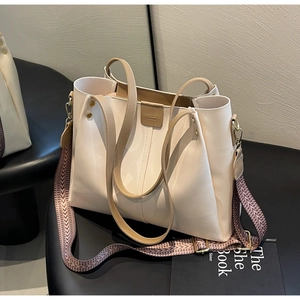 Dettaglio borsa tote color crema con hardware dorato e tracolla larga ricamata