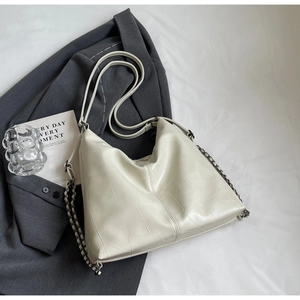 Detail of off-white lychee grain leather tote with geometric stitching and metal chain straps