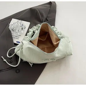 Detailed view of the pleated handbag interior with light green fabric and bow accent