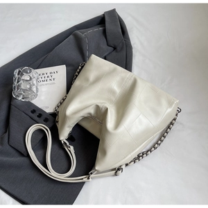 Close-up of cream puzzle-style leather tote bag with elegant metal chain strap detail