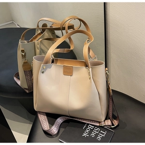 Dettaglio borsa tote beige con manici in pelle marrone e tracolla con motivi geometrici