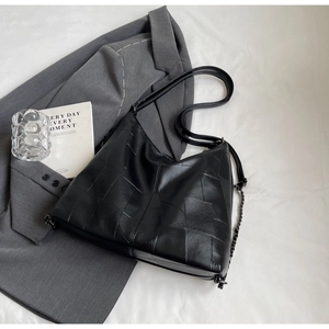 Detail of black geometric patchwork hobo bag with leather strap and chain accent