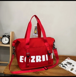 Detail of red large capacity nylon travel tote bag with white lettering and shoulder strap