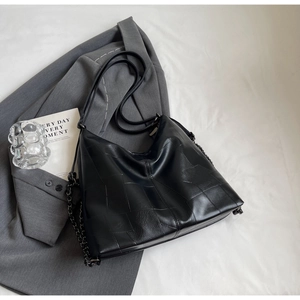 Close-up of black PU leather shoulder bag with geometric stitching and metal chain detail