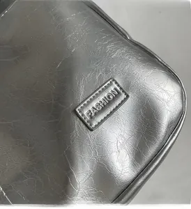 Detail of silver metallic PU leather fabric with FASHION label and pleated texture