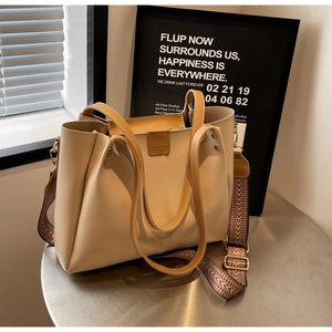 Dettaglio della borsa tote crema con ampia tracolla geometrica e patch logo in pelle