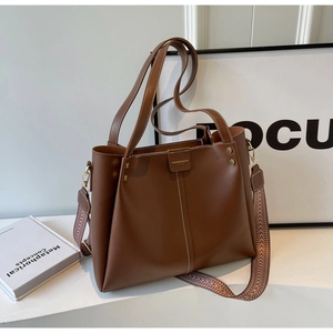Dettaglio borsa tote marrone con tracolla larga a motivo e piccolo logo dorato