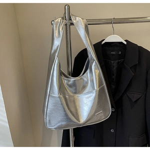 Close-up of metallic silver tote bag with crinkled texture and sleek metal logo detail