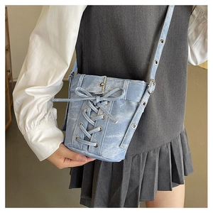 Detail der hellblauen Umhängetasche in Denim-Optik mit Kreuzschnürung und Metallschnalle