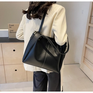 Dettaglio della borsa tote in pelle nera con cuciture bianche a contrasto e oro metallo
