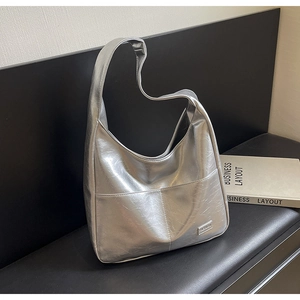 Close-up of metallic silver tote bag with pleated texture and silver brand plate