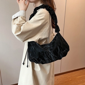 Chic black pleated dumpling bag with bow detail and ruffled shoulder strap