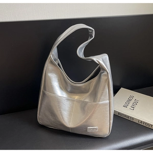 Detail of a large silver metallic tote bag with high-end pleated texture and fashion label