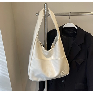 Detail of cream large tote bag featuring dual front pockets and sleek half-moon shape