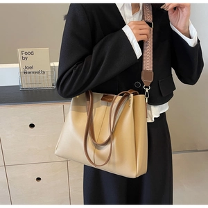 Dettaglio di una grande borsa tote beige con manici marroni e tracolla etnica in tessuto