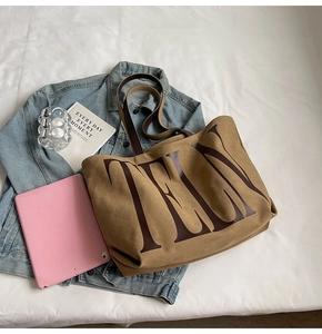 Détail du sac fourre-tout kaki avec imprimé TELY et anses marron sur tissu clair