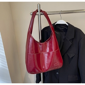 Detail of dark red high-gloss Hobo bag with white contrast stitching and front pockets
