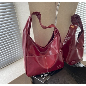 Close-up of burgundy oil wax leather tote bag with white contrast stitching and large pocket