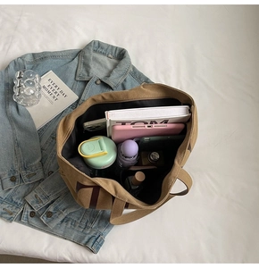 Vue détaillée du grand sac fourre-tout en toile kaki avec livres, tablette et accessoires