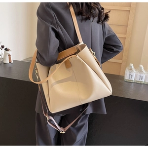Dettaglio borsa tote in pelle beige con manici marroni e tracolla in tessuto intrecciato