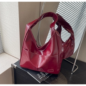Macro detail of wine red tote bag with glossy texture and contrast white stitching