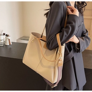 Dettaglio borsa tote beige con ampia tracolla jacquard e borchie dorate
