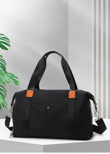 Macro view of black oxford travel bag showing orange leather accents and detachable strap