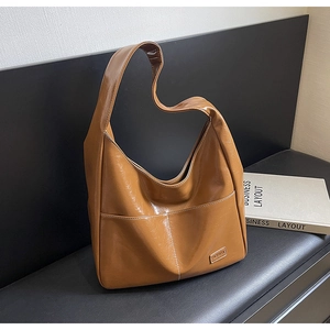 Close-up of caramel brown tote bag featuring pleated texture and FASHION metal plate