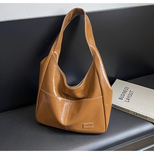 Detail of caramel high-gloss patent leather tote bag with Fashion label and hobo shape