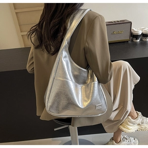 Detail of silver metallic hobo bag with vintage cracked texture worn on shoulder
