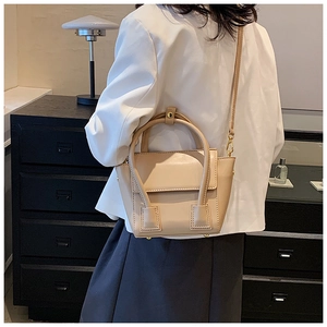 Détail de vue arrière d'un sac cabas beige minimaliste porté par un mannequin en intérieur
