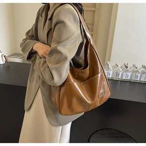 Detailed close-up of a vintage brown tote bag showing glossy leather texture and stitching
