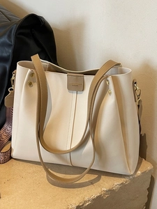 Grande borsa tote crema con manici marroni e tracolla intrecciata su pietra