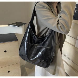 Close-up of a black glossy tote bag with crinkle texture and white stitching details