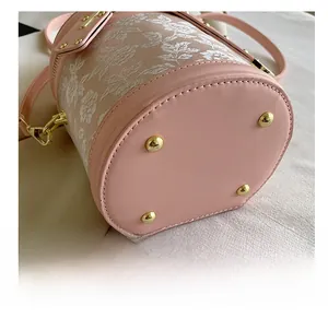 Detail of pink bucket bag base with protective gold metal studs and floral lace finish