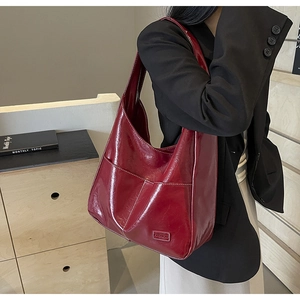 Deep burgundy large hobo shoulder bag in glossy leather worn with a black blazer