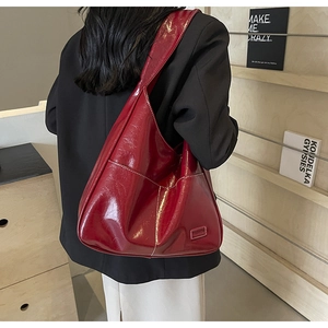 Detail of red high-gloss tote bag with side pocket and fashion label on black blazer