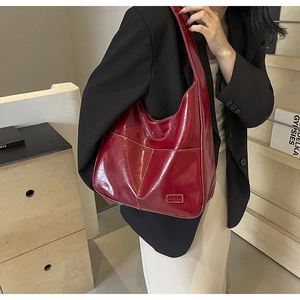 Detail of red glossy oil wax leather hobo bag with front pocket and fashion label