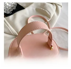Close-up of pink bucket bag with smooth leather handle and golden metal hardware