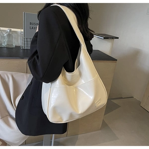Close-up of cream large tote bag in glossy textured leather worn by a model
