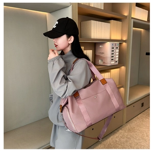 Detail of light pink waterproof nylon travel bag with side shoe compartment and leather trim