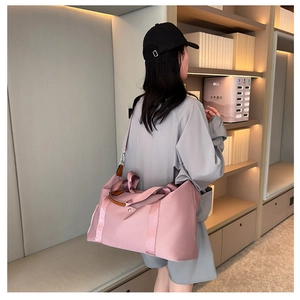 Detailed shot of large pink travel bag with brown leather handles and nylon texture