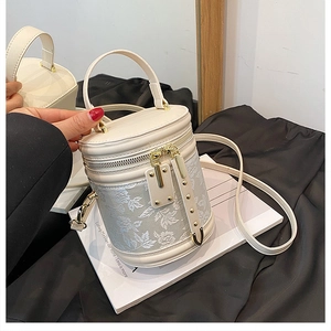 Detailed close-up of cream bucket bag with elegant white floral embroidery and gold hardware
