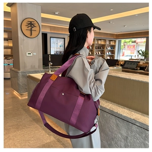 Detail of purple waterproof nylon travel bag with brown leather accents and shoulder strap