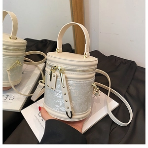 Detail of cream leather bucket bag featuring floral jacquard and gold zipper hardware