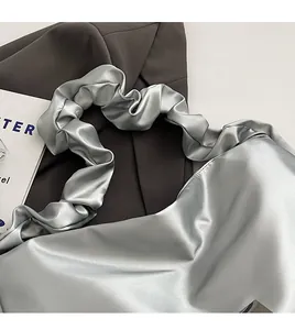Close-up of metallic silver bag with ruffled shoulder strap and satin fabric texture