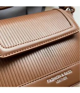 Detail of brown leather bag with vertical embossed texture and fashion logo lettering
